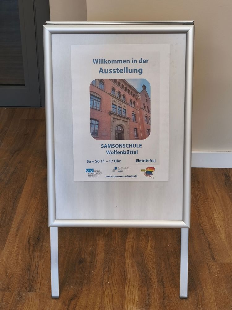 Ein Aufsteller kündigt die Öffnungszeiten der Dauerausstellung in der ehemaligen Samsonschule Wolfenbüttel an.