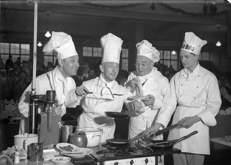 Originalbildunterschrift von 1932: Deutsche Filmschauspieler kochen um die Wette ! Auf der Berliner Kochkunstausstellung in den Ausstellungshallen am Kaiserdamm zeigten die prominentesten deutschen Schauspieler ihre Kunst im Kochen. Fritz Kampers (links) und Paul Westermeyer (rechts) bestaunen die Kochkunst des Filmkomikers Paul Grätz auf der Kochkunstausstellung.